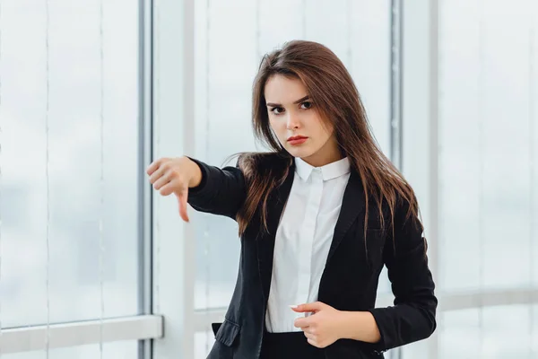 Retrato de cerca de una joven mujer seria dando el pulgar hacia abajo como si dijeras que hiciste algo mal, tu culpa. Concepto de gestos humanos negativos . —  Fotos de Stock