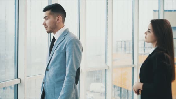 Man is looking out the panoramic window. Acquaintance of two business people in office, on the panoramic blurred background. Close up. Copy space. 4K. — Stock Video