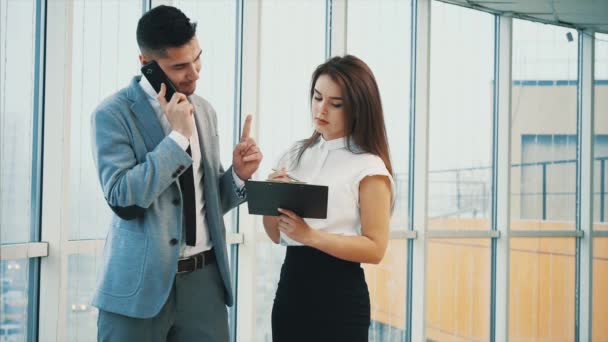 Succesvol team. Begrepen, ruimte. De baas is aan de telefoon. Hij onderscheidt documenten. Wazige witte panoramische achtergrond. Sluit maar af. 4k. — Stockvideo