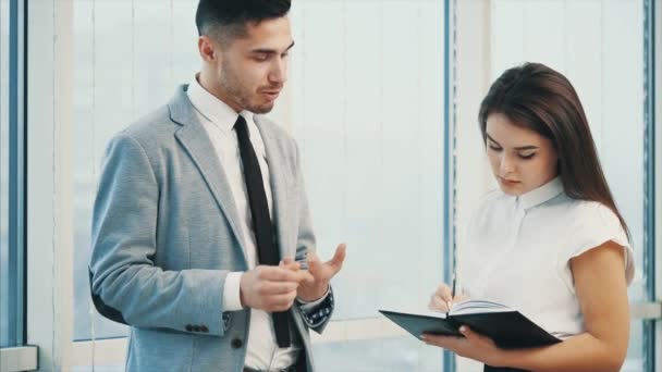 Un hombre de negocios seguro le está dando instrucciones a su compañero de trabajo. Fondo panorámico blanco borroso. De cerca. 4K . — Vídeo de stock