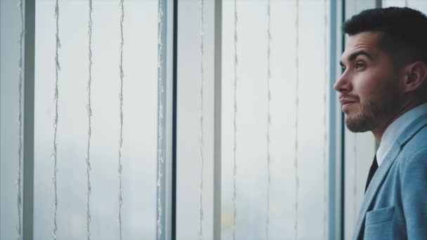 Affärsmannen kommer närmare fönstret. Människan ser sig omkring, isolerad, på vit suddig bakgrund. Uppfattat utrymme. 4k. — Stockvideo
