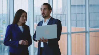 Business workers are discussing issue on the forefront. Man is on the phone on the light blurred background. Copy space. Close up. 4K.