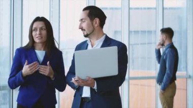 Business workers are discussing issue on the forefront. Man is on the phone on the light blurred background. Copy space. Close up. 4K.