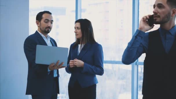 Business workers are discussing issue on the light blurred background. Man is on the phone on the forefront. Copy space. Close up. 4K. — Stok video