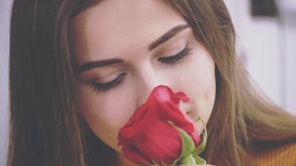 Hermosa chica morena está oliendo una rosa en un café. De cerca. Cultivo. Copiar espacio. 4K . — Vídeos de Stock