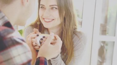 Smiling lovely couple are sitting in cafe. They are holding a cup of hot coffee. Close up view. Copy space. Action. Animation. 4K.