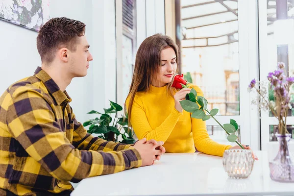 Jeune couple amoureux assis dans un café pour célébrer leur lune de miel, l'homme a apporté une rose rouge pour sa belle jeune femme,. — Photo