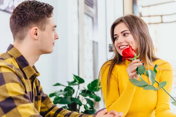 Концепція оцінки. Красива усміхнена жінка з червоною трояндою в руці дуже вдячна коханому чоловікові за такий подарунок . — стокове фото