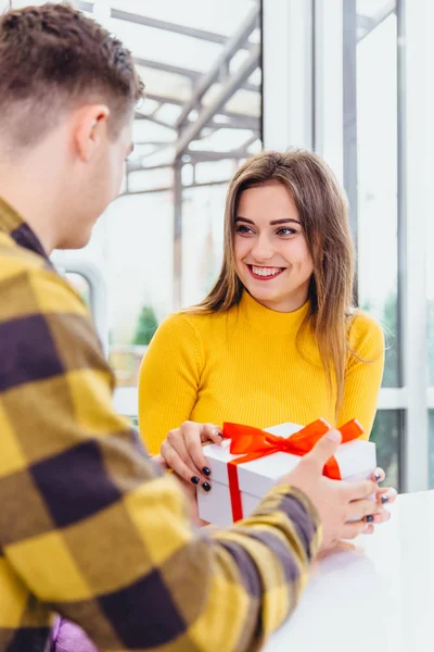 Imagem de menino afetuoso dando a namorada um presente quando se encontram na manhã de Natal . — Fotografia de Stock