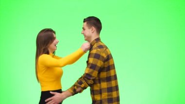 Tender loving couple is coming into a focus and smiling sincerely on a green background. Crop. Copy space. 4K.
