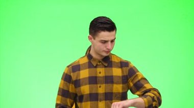 Sevecen bir çift yeşil bir arka planda tanışır. Oğlan kız arkadaşını bekliyor ve saatine bakıyor. Kapatın. Uzayı kopyala 4k.