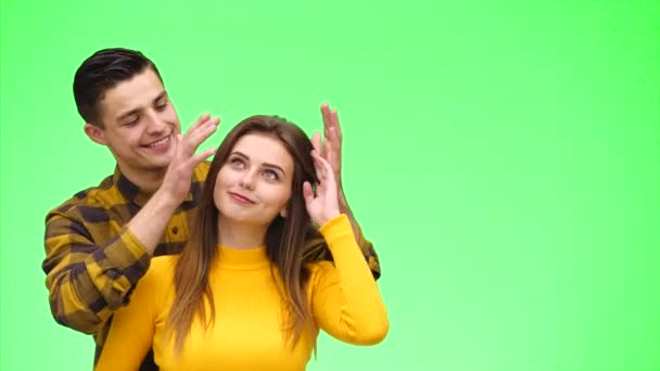 Tierna pareja amorosa está sonriendo sinceramente y acurrucándose sobre un fondo verde. De cerca. Copiar espacio. 4K . — Vídeos de Stock