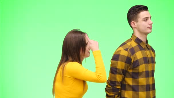 Ung kvinna grälar med ung man, är på grön bakgrund, isolerad. Uppfattat utrymme. 4k. — Stockvideo