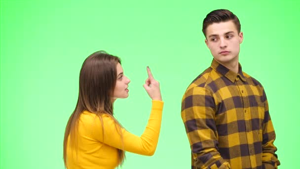 Młoda kobieta kłóci się z młodym mężczyzną, będąc na zielonym tle, odizolowana. Odbiór. 4k. — Wideo stockowe