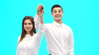 İş çifti yeni ofisin anahtarını gösteriyor. Başarılı bir anlaşma. Onlar geniş bir şekilde gülümsüyorlar. Kapatın. Uzayı kopyala 4k.