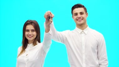 İş çifti yeni ofisin anahtarını gösteriyor. Başarılı bir anlaşma. Onlar geniş bir şekilde gülümsüyorlar. Kapatın. Uzayı kopyala 4k.