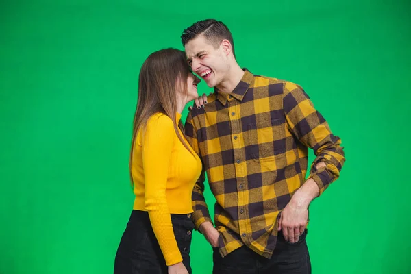 Portrait of girl whispering into mans ear, telling him something really funny because he is smiling desparately. — Stockfoto