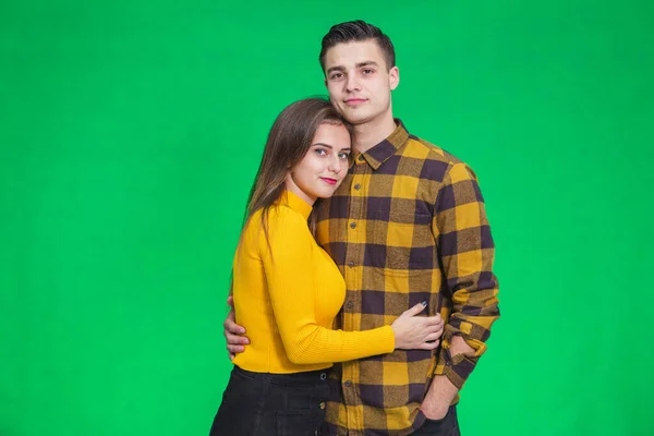 Inspired young people looking ahead, dreaming about their future together, while standing on green background, embracing. — ストック写真