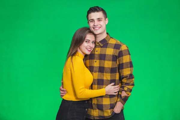 Stylish couple in autumn outfits posing isolated on green background. — Stockfoto