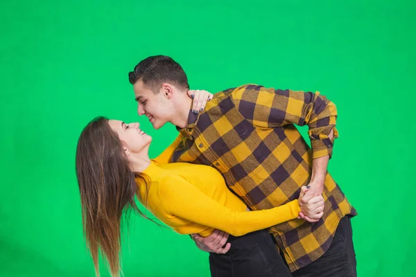 Young beautiful couple in love, dancing on green background, celebrating some special occasion.