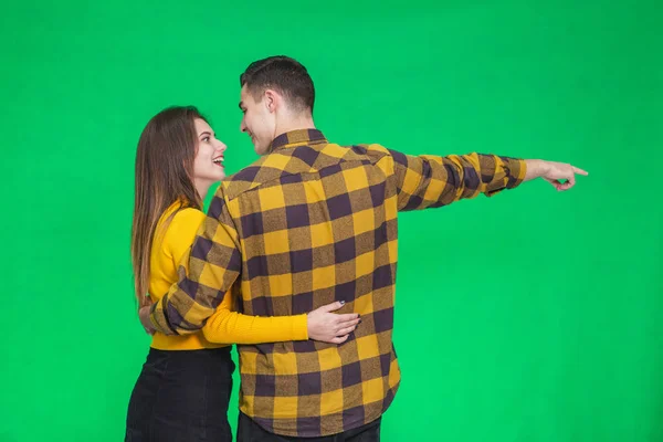 Back view of young couple pointing far away over green background — Stockfoto