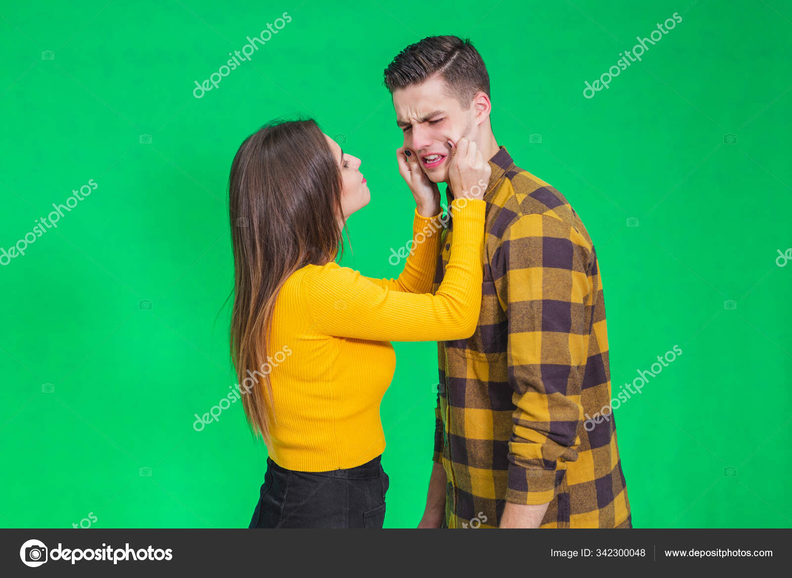 Girl Pinching Guys Cheeks Making Fyn He Is Scowling His Face Looking