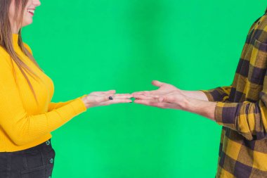 Beautiful couple standing together over green background holding palms open with copy space, advertising a product or idea.