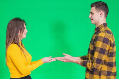 Couple dressed in yellow and black clothes, presenting something, holding hands opened together.