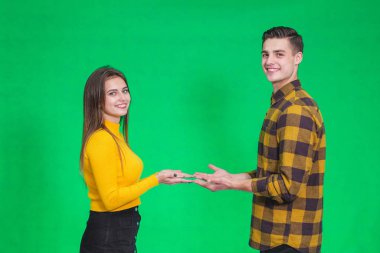 Couple dressed in yellow and black clothes, presenting something, holding hands opened together.
