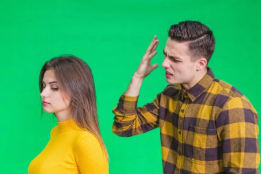 Man extremely angry at girlfriend, shouting at her, warnig with fist, she stands back to her, not paying attention.