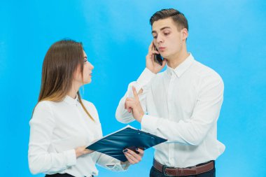 Young secretary distracts boss to sign a document while he is talking on mobile phone.