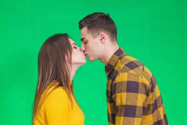 Happy calm man and woman enjoying peace of mind and kissing against green background. — Stockfoto