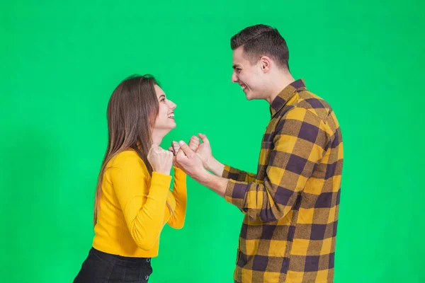 Jovem casal alegre apertando os punhos, dizendo sim, celebrando seu sucesso sobre fundo verde . — Fotografia de Stock