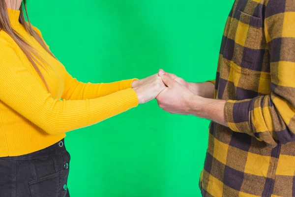 Cropped shot of hands in hands together over green background. — Stockfoto