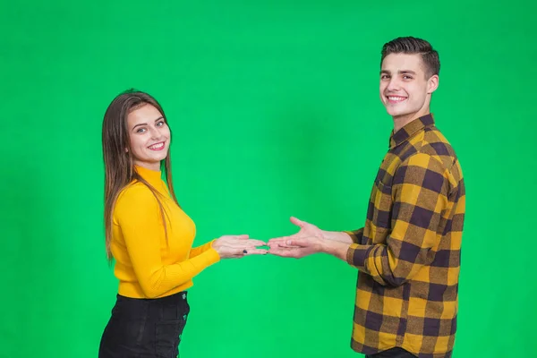 Couple dressed in yellow and black clothes, presenting something, holding hands opened together. — Stockfoto