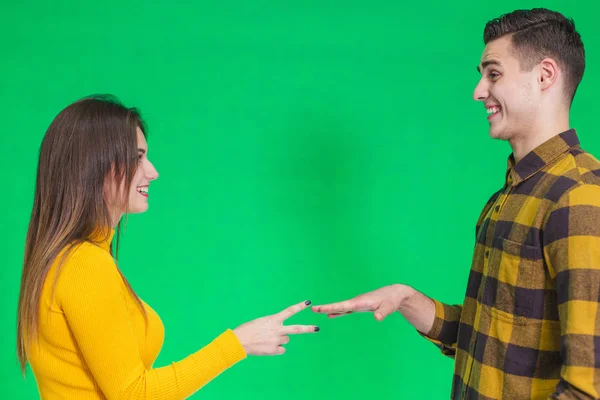 Two people playing rock paper scissors isolated on green background. — Stockfoto