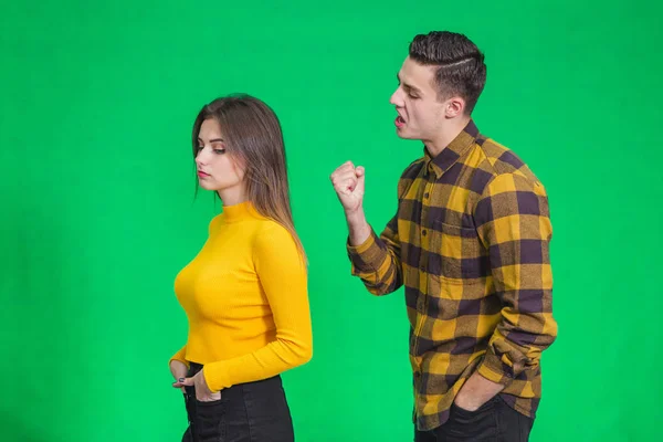 Man extremely angry at girlfriend, shouting at her, warnig with fist, she stands back to her, not paying attention. — Stockfoto