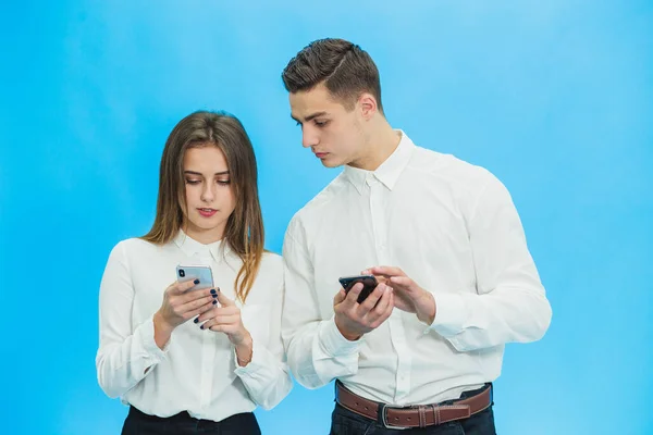 Gente de negocios que usa teléfonos inteligentes, completando algunas tareas de trabajo contra fondo azul . — Foto de Stock