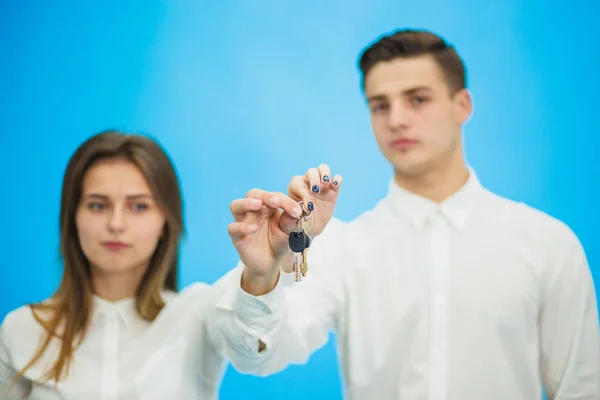 Happy copule of realtors showing keys to perfect apartment over blue background. — Stockfoto