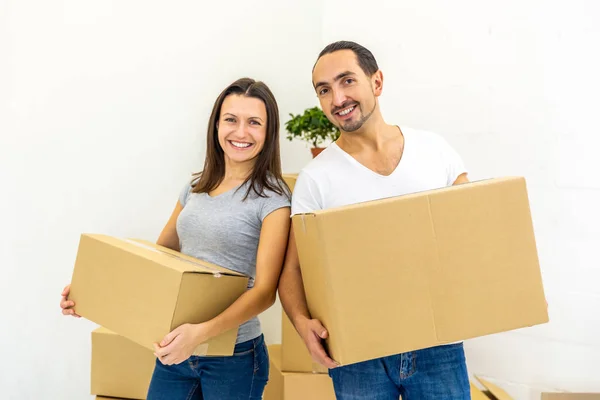 Pareja feliz mirando a la cámara, sosteniendo cajas, lista para mudarse a su nueva casa . —  Fotos de Stock