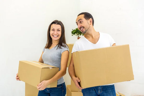 Casal feliz olhando para a câmera, segurando caixas, pronto para se mudar para sua nova casa . — Fotografia de Stock