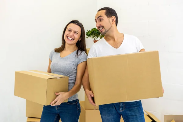 Happy couple looking at camera, holding boxes, ready to move into their new house. — Stock Photo, Image