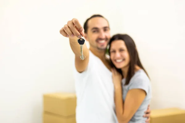 Imagen borrosa de la familia joven extremadamente feliz porque compraron una casa nueva. Hombre mostrando las teclas de la cámara . —  Fotos de Stock