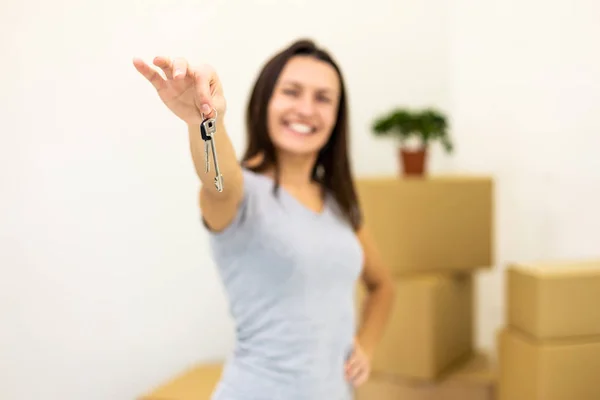 Female holding house keys on key chain and smiling to the camera with beaming smile. Concept for buying real estate. — Stockfoto