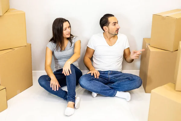 Embalado e pronto para se mudar para casa nova. Jovens cônjuges entusiasmados sentados entre caixas de papelão prontas para se mudar . — Fotografia de Stock