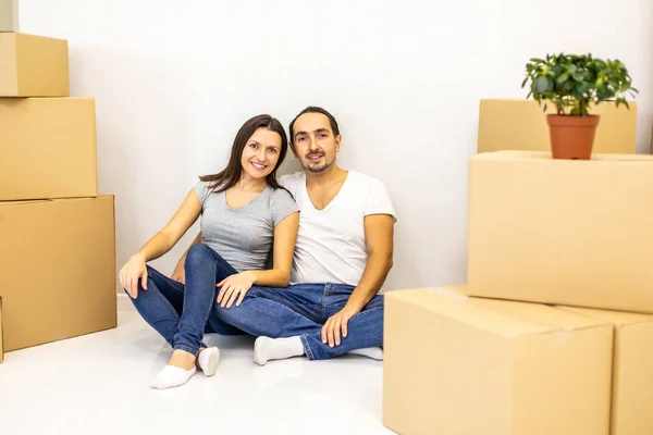 Embalado e pronto para se mudar para casa nova. Jovens cônjuges entusiasmados sentados entre caixas de papelão prontas para se mudar . — Fotografia de Stock