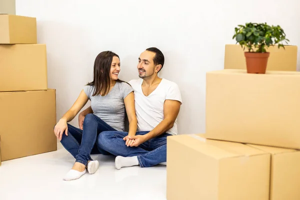 Emballé et prêt à emménager dans une nouvelle maison. Jeunes conjoints excités assis parmi des boîtes en carton prêts à déménager . — Photo