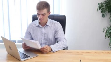 Genç işadamı büroda evrak okuyor. Kapatın. Uzayı kopyala 4k.