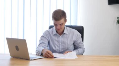Genç işadamı büroda evrak okuyor. Çöpe atıyor. Kapatın. Uzayı kopyala 4k.