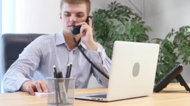 Genç işadamı ofis koltuğunda oturan dizüstü bilgisayarında yeni bir proje için zevkle çalışıyor. Ekin. Arka plan bulanık. Kapatın. Uzayı kopyala Ekin. 4k.